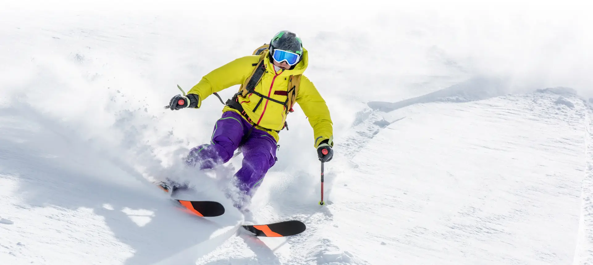 Skier carving powder in yellow jacket